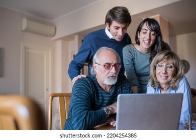 Family Of Four Indoors At Home Using Computer Together Surfing Web Doing Videocall