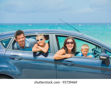 A Family Of Four, Mother, Father, Son And Daughter Driving In A Car On A Sunny Day In Hot Location, Backround Sea