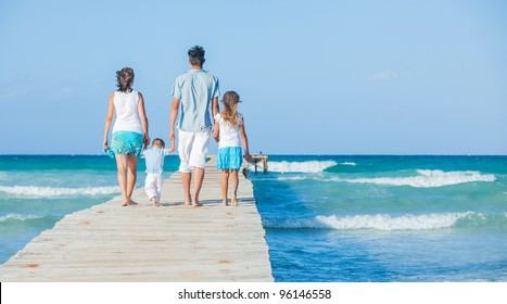 Family of four on wooden jetty by the ocean. Back view - Powered by Shutterstock