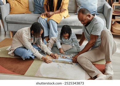 Family of four sitting on floor engaging in puzzle activity while showing close bond and teamwork in well-furnished and cozy living room setting - Powered by Shutterstock