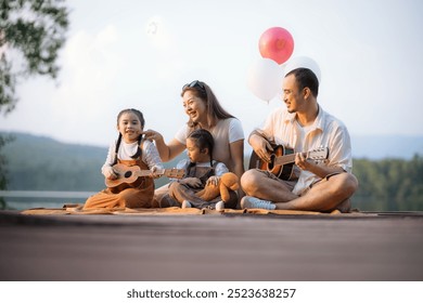 A family of four is sitting on a wooden deck, playing guitars and enjoying a balloon. Scene is happy and relaxed, as the family is spending quality time together and having fun - Powered by Shutterstock