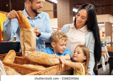 Family Of Four In The Supermarket Doing Daily Shopping Together Children Taking Fresh Bread Greedy Smiling Happy