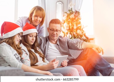 Family Of Four Using Digital Tablet At Home During Christmas