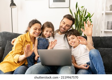 Family Of Four Using Laptop For Video Connection With Grandparents Or Family. Multiracial Mom, Dad And Two Kids Waving In Webcam Of The Laptop, Video Call, Virtual Meeting Concept