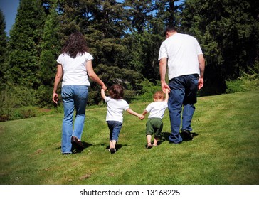 Family Of Four Walking Hand In Hand Away From The Camera.