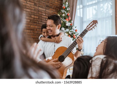 family and friend singing a song together. father playing guitar during christmas - Powered by Shutterstock