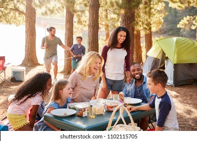 Family With Friends Camp By Lake On Hiking Adventure In Forest