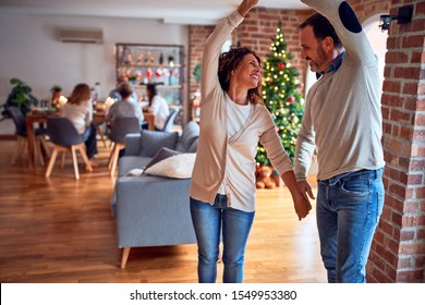 Family and friends dining at home celebrating christmas eve with traditional food and decoration, romantic couple dancing in love - Powered by Shutterstock