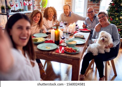 Family and friends dining at home celebrating christmas eve with traditional food and decoration, taking a selfie picture together