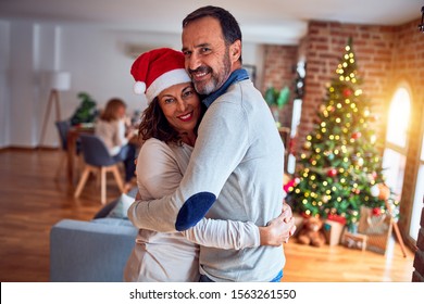 Family and friends dining at home celebrating christmas eve with traditional food and decoration, romantic senior couple hugging in love - Powered by Shutterstock