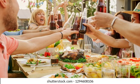 Family and Friends Gathered Together at the Table Raise Glasses and Bottles To Make a Toast and Clink Glasses. Big Family Garden Party Celebration.