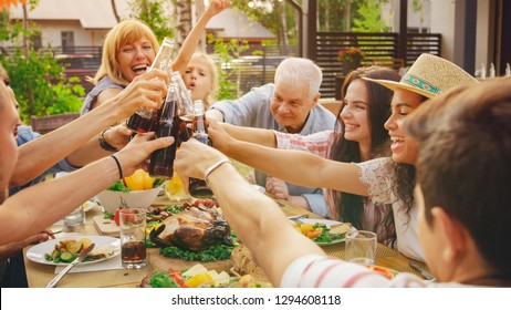 Family and Friends Gathered Together at the Table Raise Glasses and Bottles To Make a Toast and Clink Glasses. Big Family Garden Party Celebration.