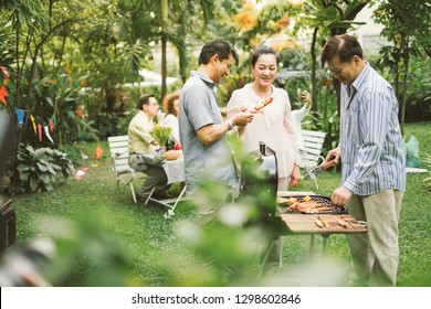 Family And Friends Gathered Together At The Table.Cooking Bbq Outdoor For A Group Of Friends.Big Family Garden Party Celebration.Diverse Neighbors Drinking Party Yard Concept.