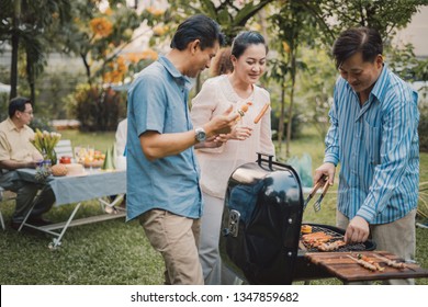 Family And Friends Gathered Together At The Table.Cooking Bbq Outdoor For A Group Of Friends.Big Family Garden Party Celebration.Diverse Neighbors Drinking Party Yard Concept.