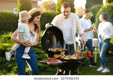 Family with friends having barbecue party outdoors - Powered by Shutterstock