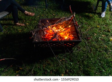 Family And Friends Sit Around A Backyard Fire Pit And Toast Smores