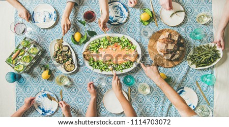 Family or friends summer party or seafood dinner. Flat-lay of group of mutinational people with different skin color at big table eating delicious food together. Summer gathering or celebration