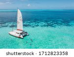 Family and friends swimming near a beautiful catamaran in the paradise turquoise lagoon of the east coast of Mauritius