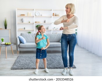 Family Fun. Full Body Length Portrait Of Positive Grandmother Moving And Dancing To Music With Her Little Grandchild. Girl And Granny Enjoying Spending Time Together In Living Room