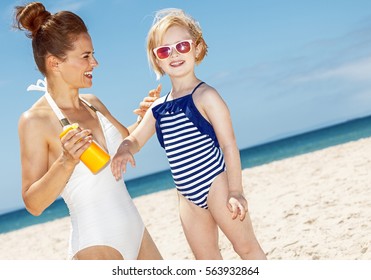 Family Fun On White Sand. Happy Mother Applying Sunscreen On Child's Arm At Sandy Beach On A Sunny Day