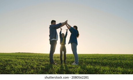 Family Game Outdoors. Child Mom And Dad Play Together Building A House Symbol At Sunset. Happy Family Dreams Of Their Own House In The Summer Park In The Sun. Family Happiness Concept, Childhood Dream