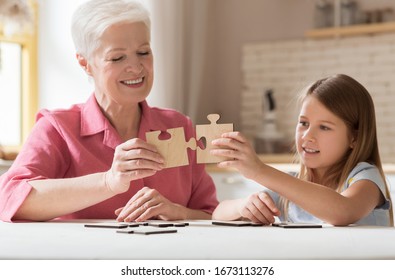 Family games. Lovely girl and her grandma solving jigsaw puzzle together at home - Powered by Shutterstock