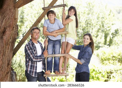 Family In Garden By Treehouse