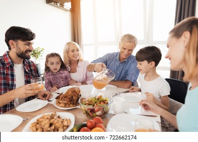 The family gathered at the festive table for Thanksgiving. The old man pours juice on the glasses. On the table is a baked turkey and other food - Powered by Shutterstock