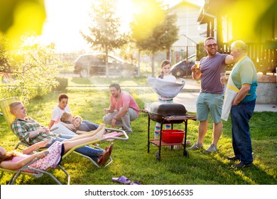 Family Gathered And Is Having A Picnic And Grilling In Their Backyard On Beautiful Spring Day.