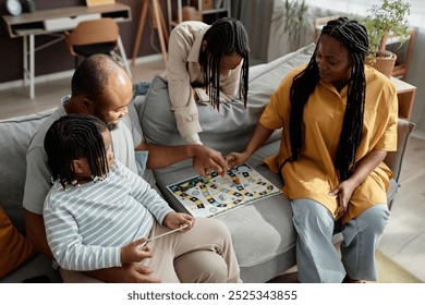 Family gathering around a board game in cozy living room while spending quality time together depicting engagement and togetherness - Powered by Shutterstock