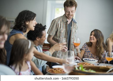 A Family Gathering For A Meal. Adults And Children Around A Table.