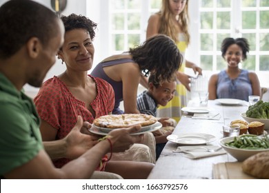 A family gathering, men, women and children around a dining table sharing a meal. - Powered by Shutterstock