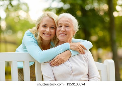 Family, Generation And People Concept - Happy Smiling Young Daughter With Senior Mother Sitting On Park Bench And Hugging