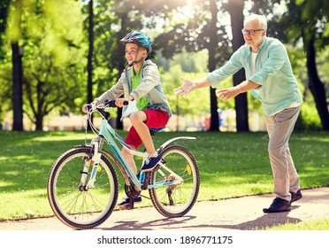 family, generation, safety and people concept - happy grandfather teaching boy how to ride bicycle at summer park - Powered by Shutterstock