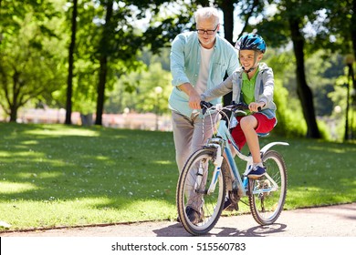 family, generation, safety and people concept - happy grandfather teaching boy how to ride bicycle at summer park - Powered by Shutterstock