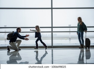 Family Getting Back Together After Time Apart. Glad Child Running Towards Daddy. Mom Is Looking At Them With Joy