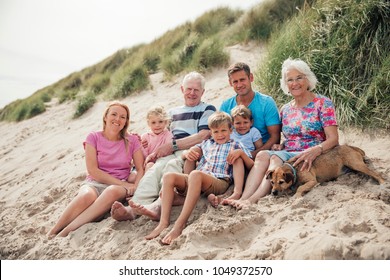 Family getting their photo taken as they sit all together on a sand dune.