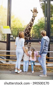 Family With Giraffe In Zoo