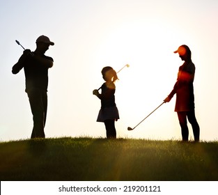 Family of a golfers playing golf at sunset