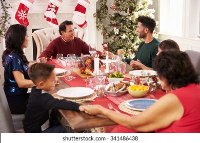 Family With Grandparents Saying Grace Before Christmas Meal