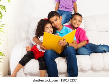 Family, Group Of Four Kids With Older Brother Reading Books To Brothers And Sister Hugging Little Girl