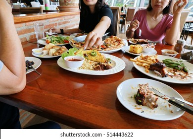 Family Group Hand Eating Big Meal With Pizza , Rib Steak ,taco And Salad On Wooden Table Background, Dinner Celebrate.