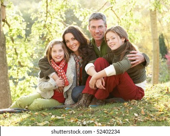 Family Group Relaxing Outdoors In Autumn Landscape