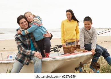 Family Group Sitting On Boat With Fishing Rod On Winter Beach