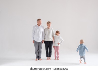Family is growing up. Positive dad charming pregnant mother eldest daughter and running baby son posing barefoot in the studio. Creative Family Photos Concept. Copyspace