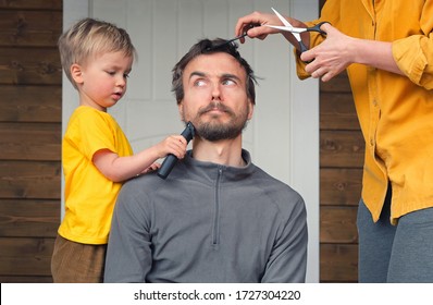 Family haircut at home during quarantine lockdown when closed all hairdressers. Mother cutting hair to father and little child boy cut dad beard with clipper. Beauty and selfcare at home lifestyle.
