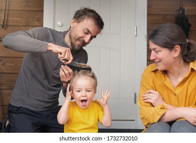 Family Haircut At Home During Quarantine, Domestic Hairdressers. Father And Mother Cuts His Son Hair, Child Boy Screaming. Beauty And Selfcare At Home, Crazy Lifestyle During Lockdown.