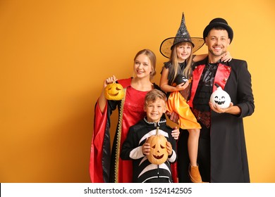 Family In Halloween Costumes On Color Background