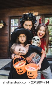 family in halloween costumes, with spooky skull and bucket of candies grimacing and growling at camera - Shutterstock ID 2042894714