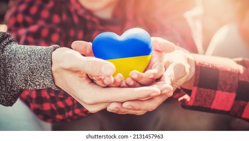 Family hands holding a heart in ucrainian colours. Peace and no war concept